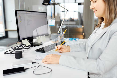 Image of businesswoman with notebook and computer at office