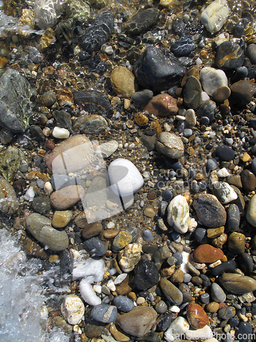Image of Wet different sea pebbles on the beach