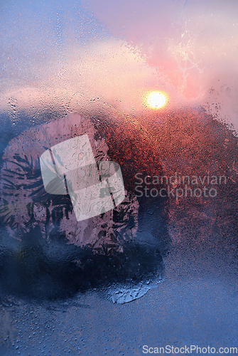 Image of Ice patterns, water drops and sunlight on a winter window glasss