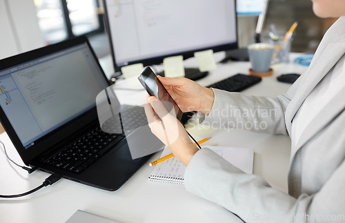 Image of businesswoman with smartphone working at office