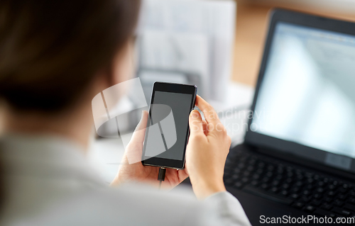 Image of businesswoman with smartphone working at office