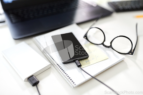 Image of smartphone with power bank on table at office