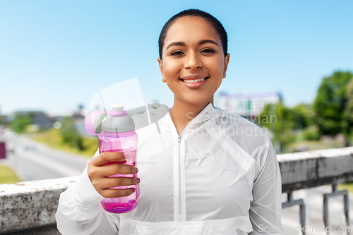 Image of african american woman drinking water from bottle