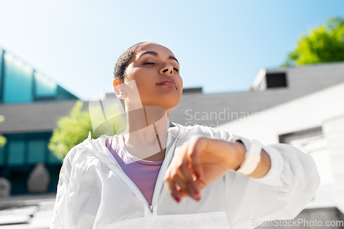 Image of young woman with smart watch breathing outdoors