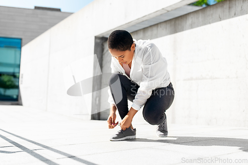 Image of african american woman tightening sneakers