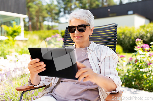 Image of happy senior woman with tablet pc at summer garden