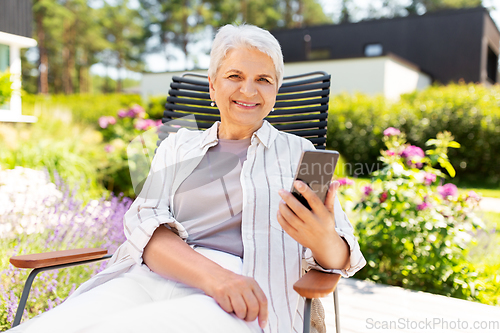 Image of happy senior woman with phone at summer garden