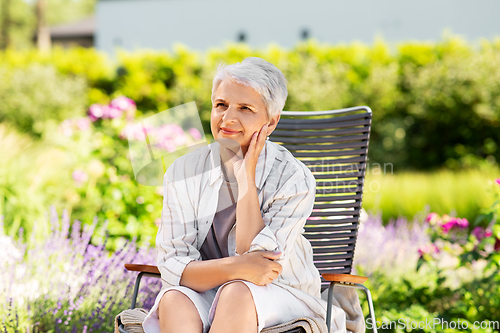 Image of happy senior woman resting at summer garden