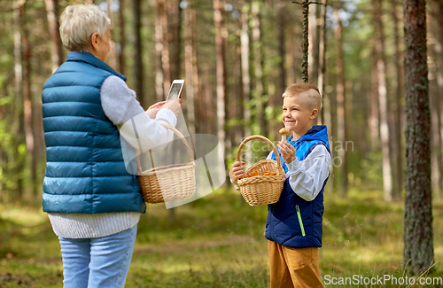 Image of grandmother photographing grandson with mushrooms