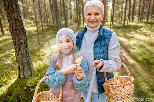 Image of grandma with granddaughter taking selfie in forest