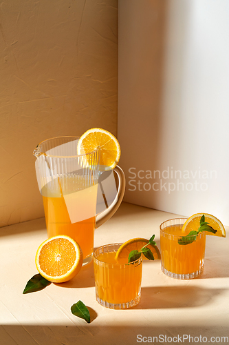 Image of glasses with orange juice and peppermint on table