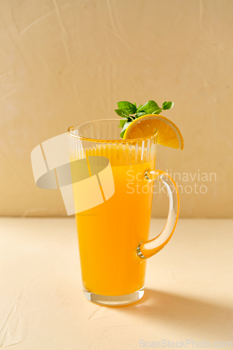 Image of jug with orange juice and peppermint on table