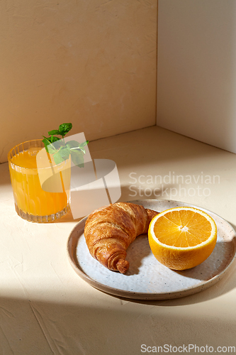 Image of glass of orange juice and croissant on plate