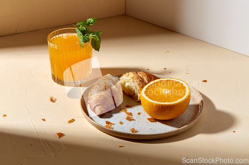 Image of glass of orange juice and croissant on plate