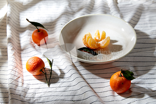 Image of still life with mandarins on plate over drapery