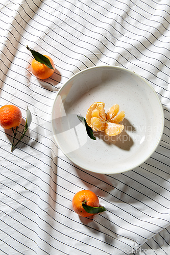 Image of still life with mandarins on plate over drapery