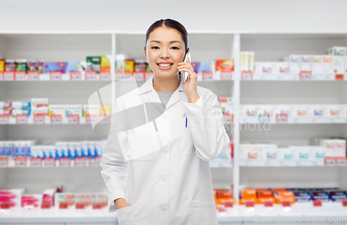 Image of asian pharmacist calling on phone at pharmacy