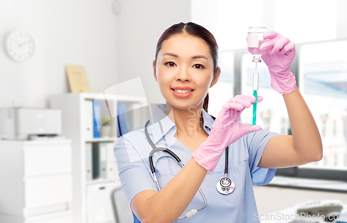 Image of happy asian female nurse with syringe at hospital