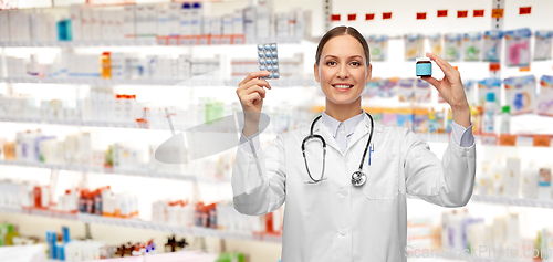 Image of smiling female doctor holding medicine pills