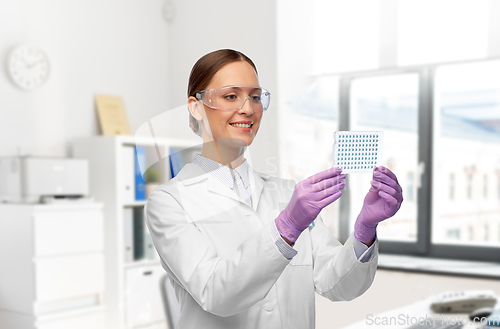 Image of female scientist in goggles with chemical sample