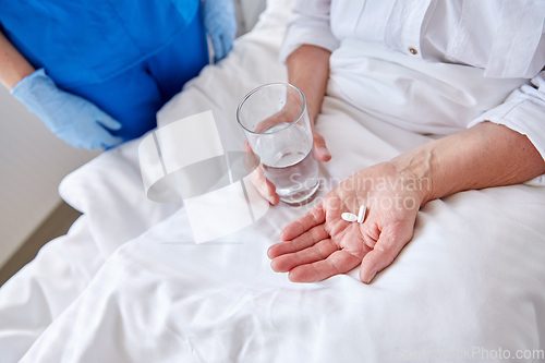 Image of nurse giving medicine to senior woman at hospital