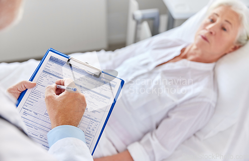 Image of senior woman and doctor with clipboard at hospital