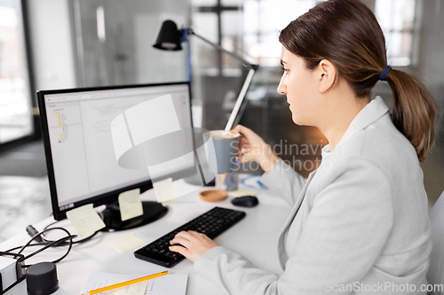 Image of businesswoman with computer and coffee at office