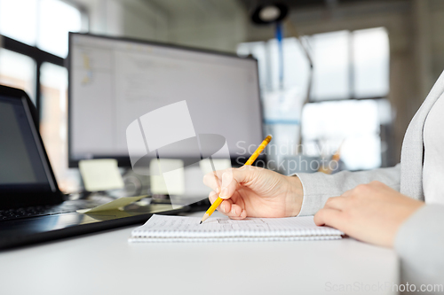 Image of businesswoman with notebook and laptop at office