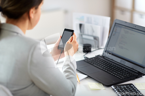 Image of businesswoman with smartphone working at office