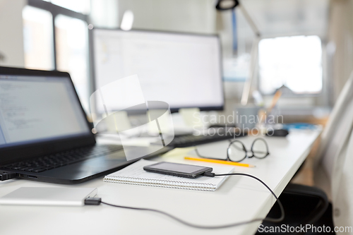 Image of smartphone with powerbank on table at office