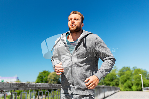 Image of happy young man running across city bridge