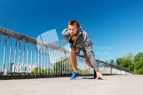 Image of young man running across city bridge