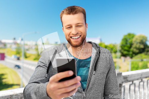 Image of smiling young man with earphones and smartphone