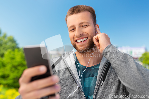 Image of smiling young man with earphones and smartphone