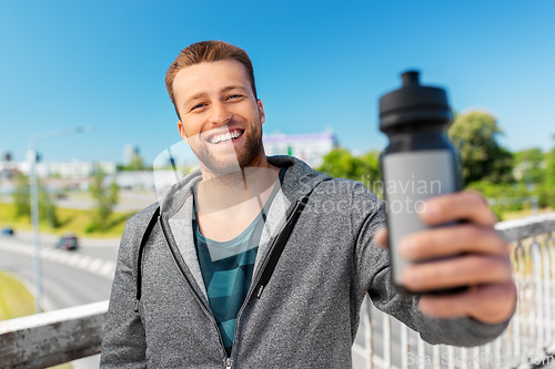 Image of happy young man with sports bottle