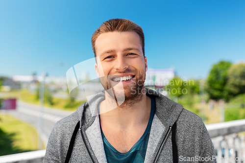 Image of portrait of happy smiling young man outdoors