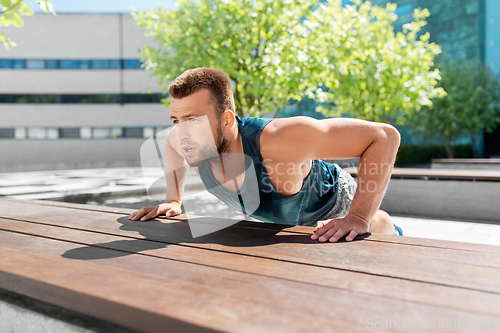 Image of young man doing push ups on city street