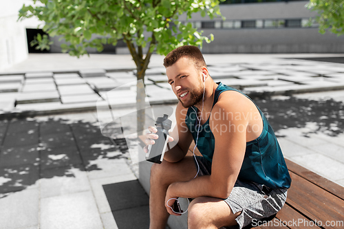Image of sportsman with earphones and bottle in city