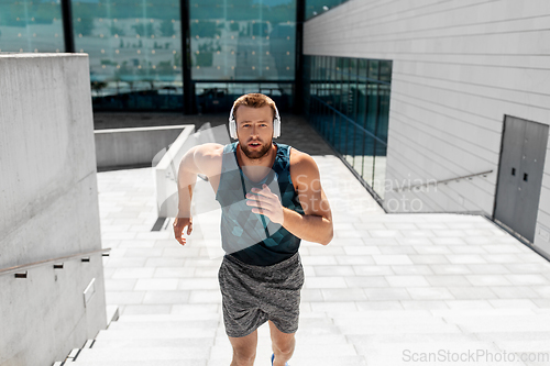 Image of young man in headphones running upstairs outdoors