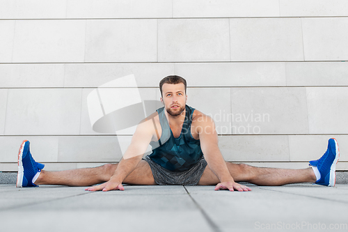 Image of man doing sports and stretching outdoors