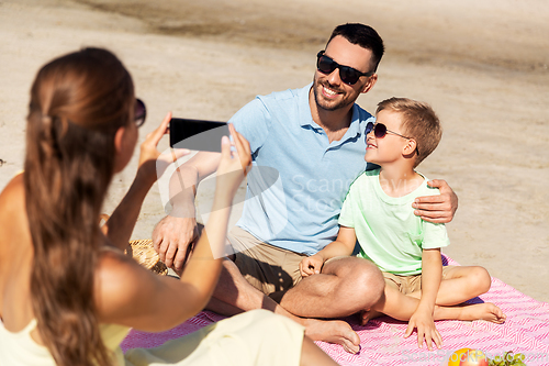 Image of family with smartphone photographing on beach