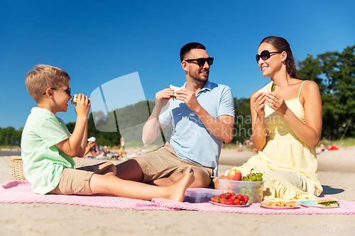 Image of happy family having picnic on summer beach