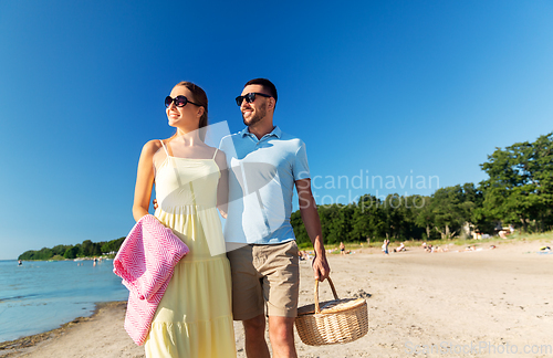 Image of happy couple with picnic basket walking on beach