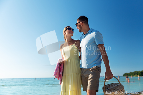 Image of happy couple with picnic basket walking on beach