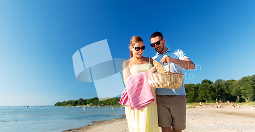 Image of happy couple with picnic basket walking on beach