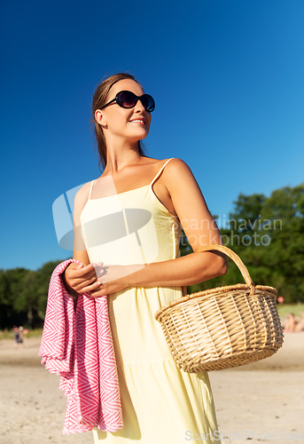 Image of happy woman with picnic basket on summer beach