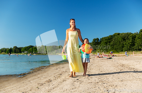 Image of mother and daughter with ball walking along beach