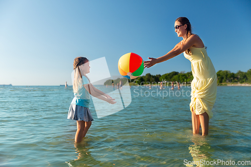 Image of mother and daughter playing with ball on beach