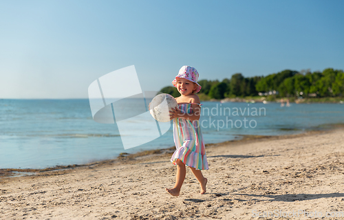 Image of happy baby girl with ball running on summer beach