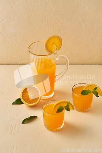 Image of glasses with orange juice and peppermint on table
